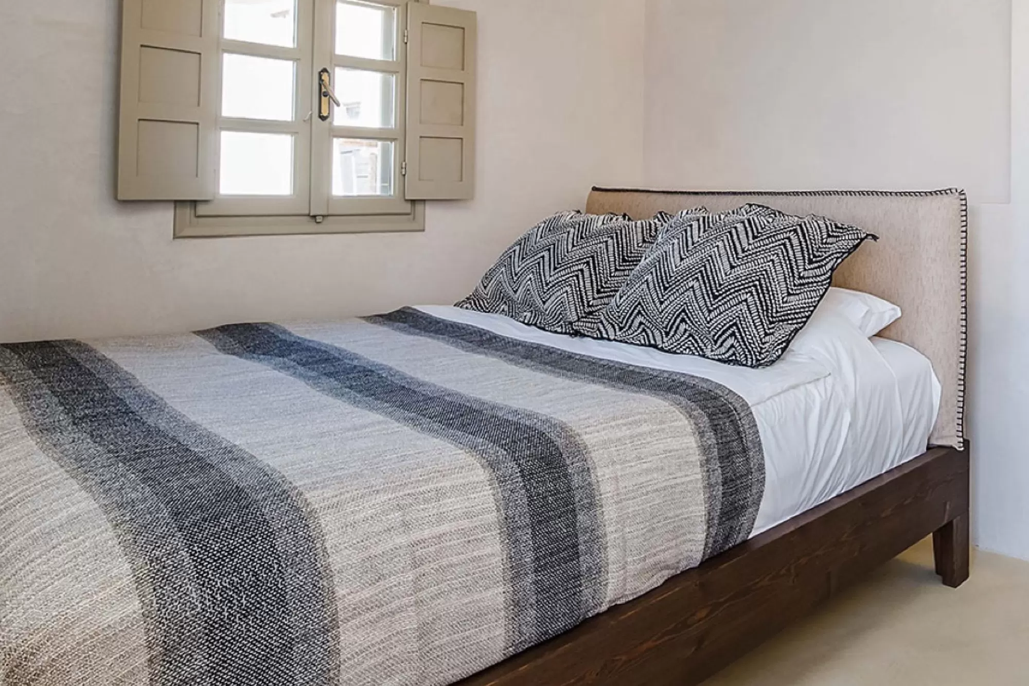 Bedroom with woven textiles and timber shutters at Phaos 1870