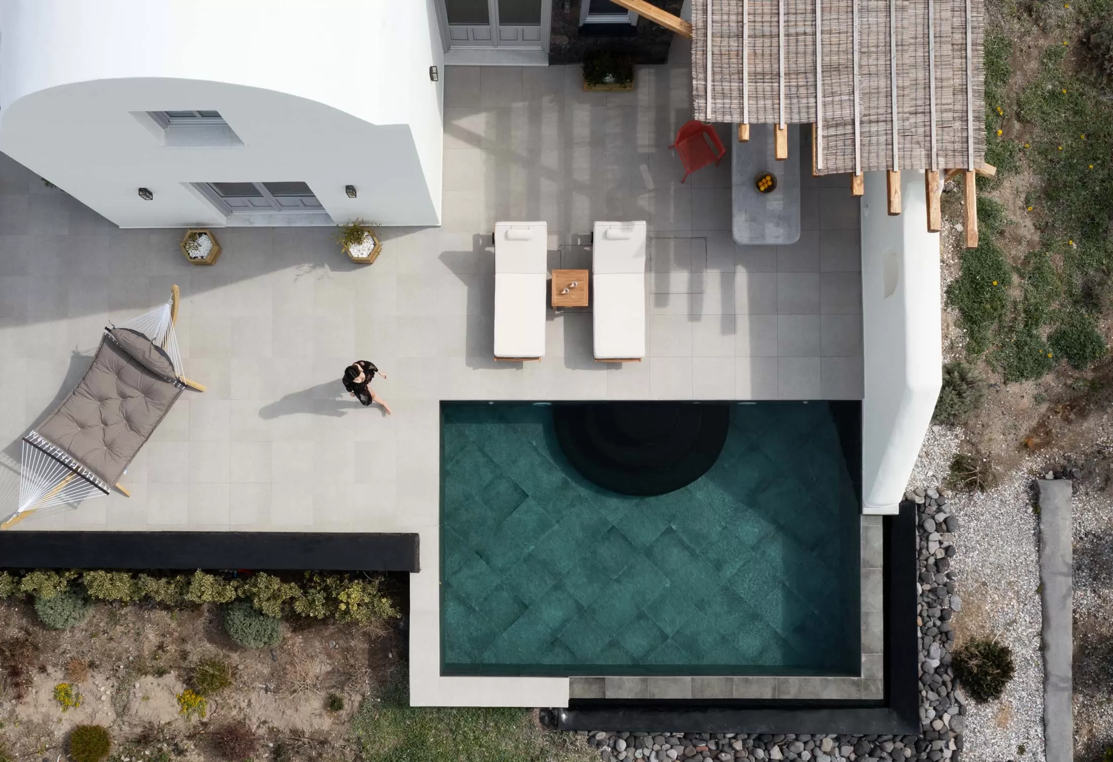 Aerial view of a villa terrace and private pool among the fields of Oia