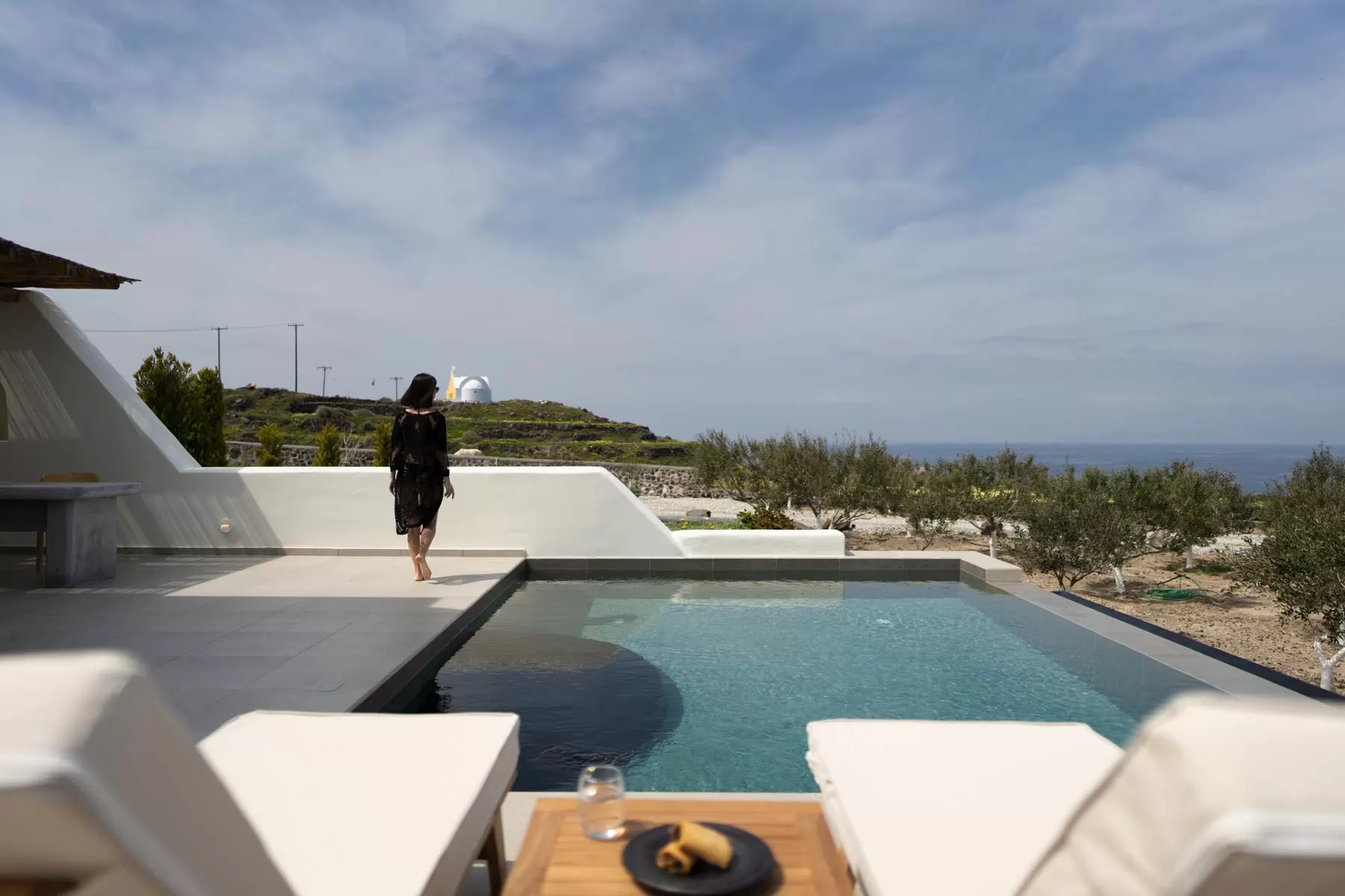 Guest walking beside a villa's private pool in Oia