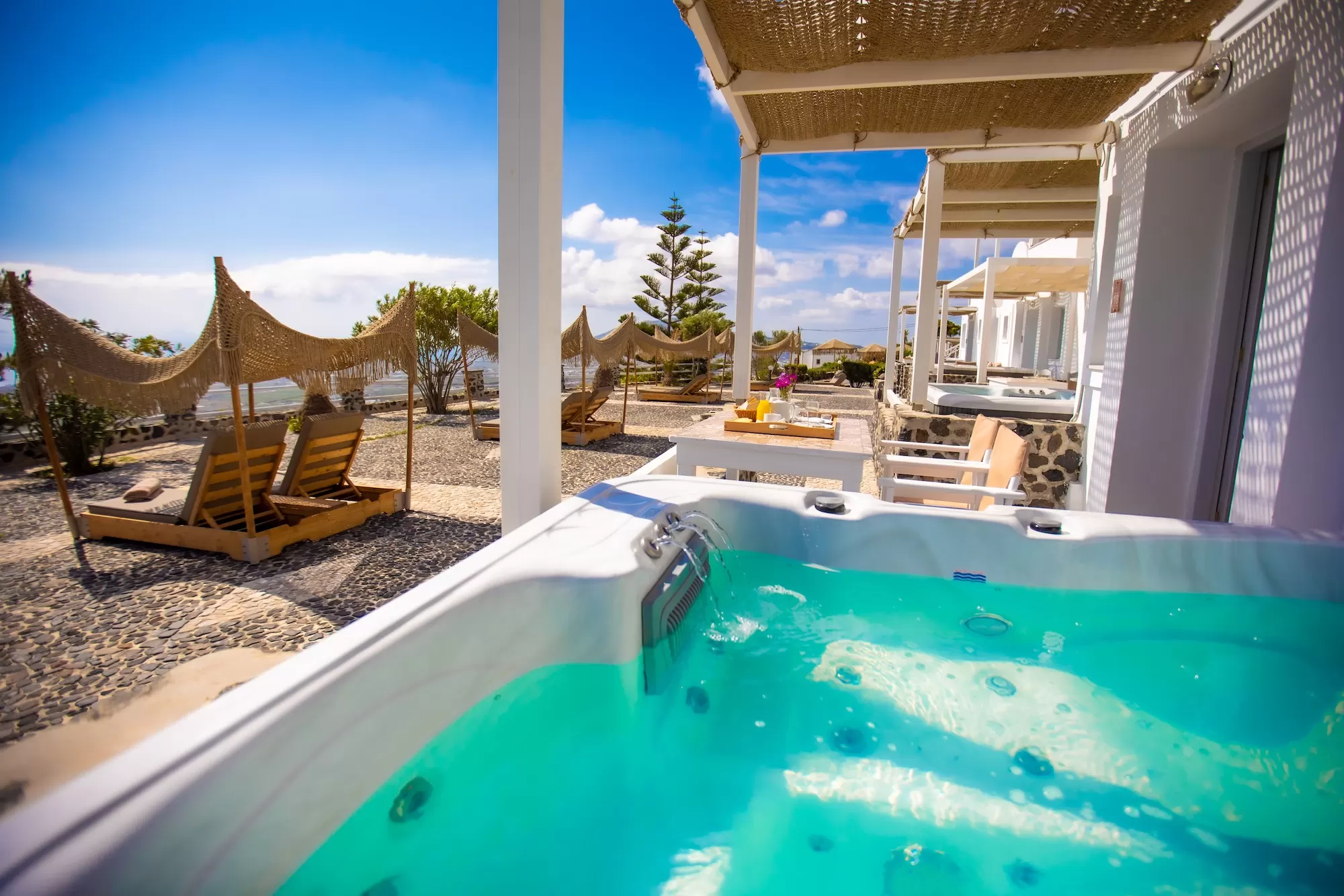 Hot tub and shaded terrace overlooking the Aegean at Phaos Santorini Suites