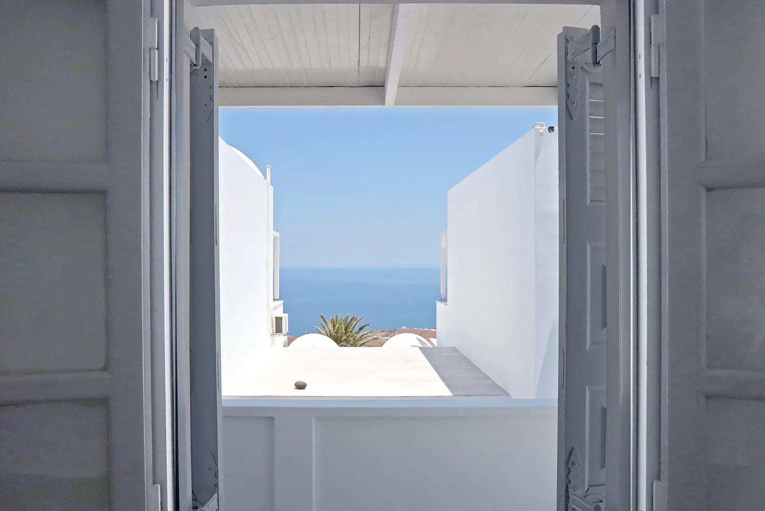 Doorway framing the Aegean from a suite at Phaos Santorini Suites