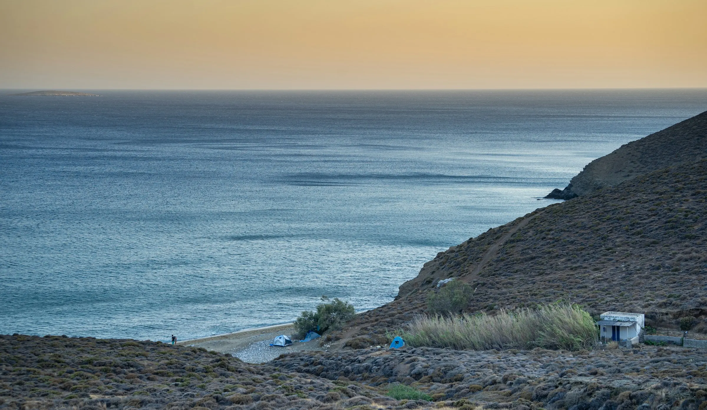 Rocky coastline and calm sea at dusk, Anafi